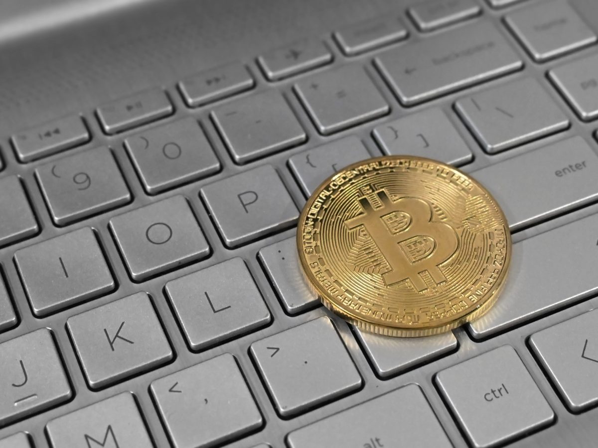 Bitcoin coin resting on laptop keyboard, symbolising digital currency and cryptocurrency investment