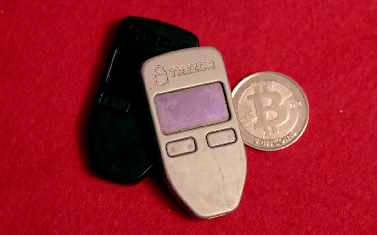 Two Trezor One bitcoin hardware wallets and a Casascius physical bitcoin coin