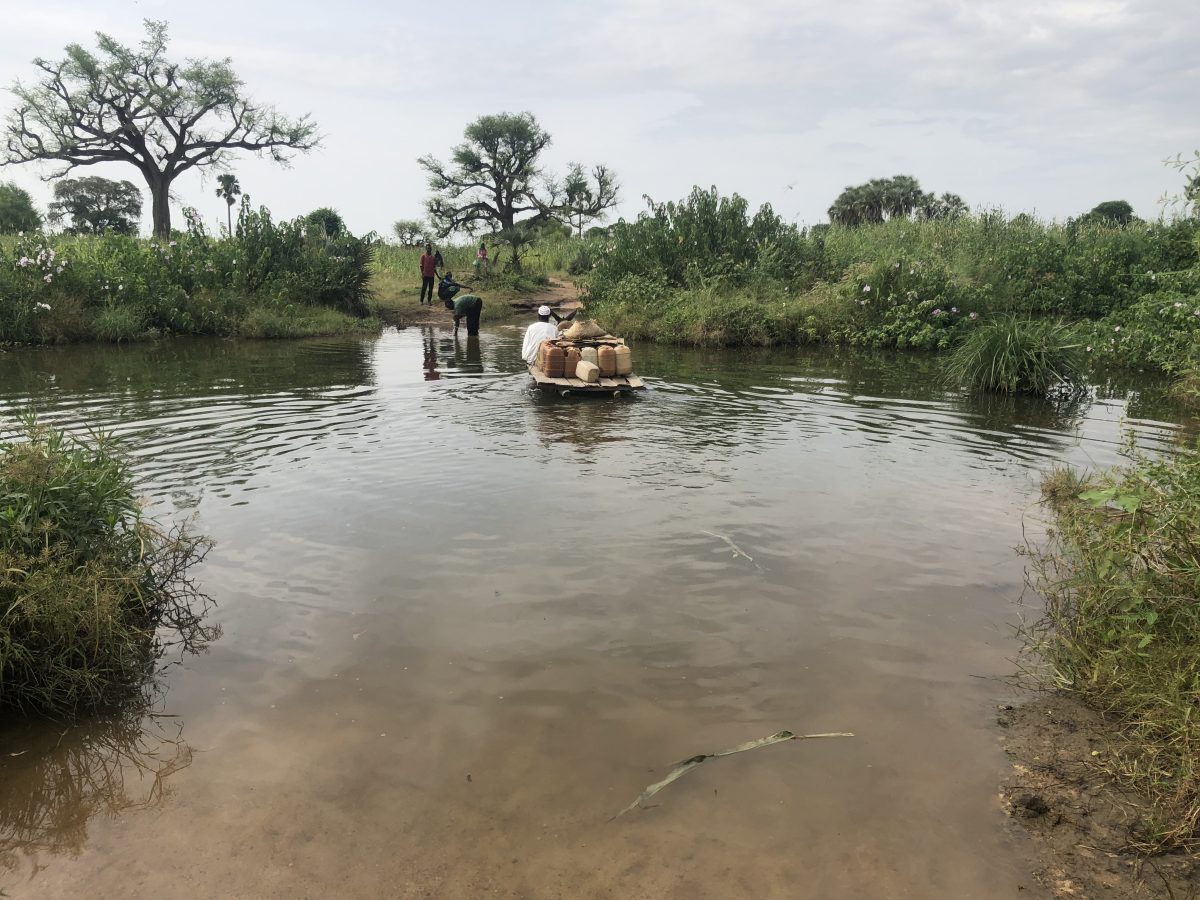 People crossing a river in Darfur, Sudan, illustrating the ongoing humanitarian crisis