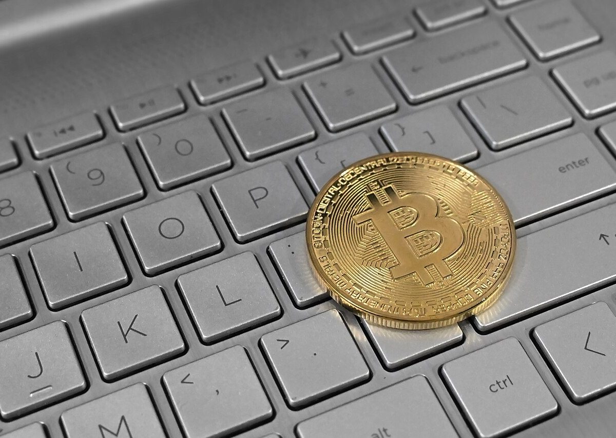 Bitcoin cryptocurrency coin placed on a laptop keyboard, representing digital asset trading
